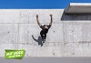 Ein Parkourläufer macht einen Salto an einer Betonwand 