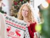 Schrottwichteln: Frau hält skeptisch ihren erwichtelten Weihnachtspullover